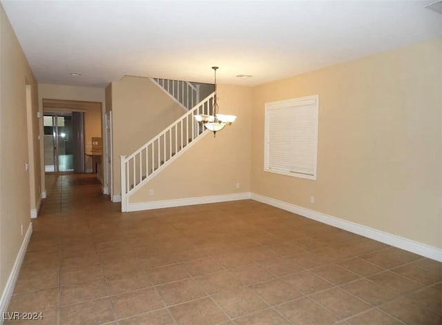 empty room with tile patterned floors and a chandelier