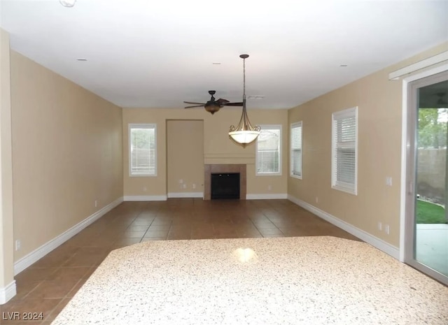 unfurnished living room with a fireplace, tile patterned flooring, ceiling fan, and a healthy amount of sunlight