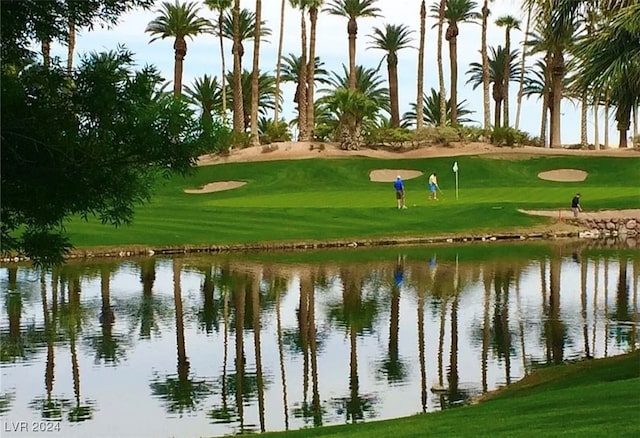 view of property's community with a water view and a lawn