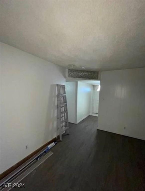 unfurnished room with a textured ceiling and dark hardwood / wood-style floors