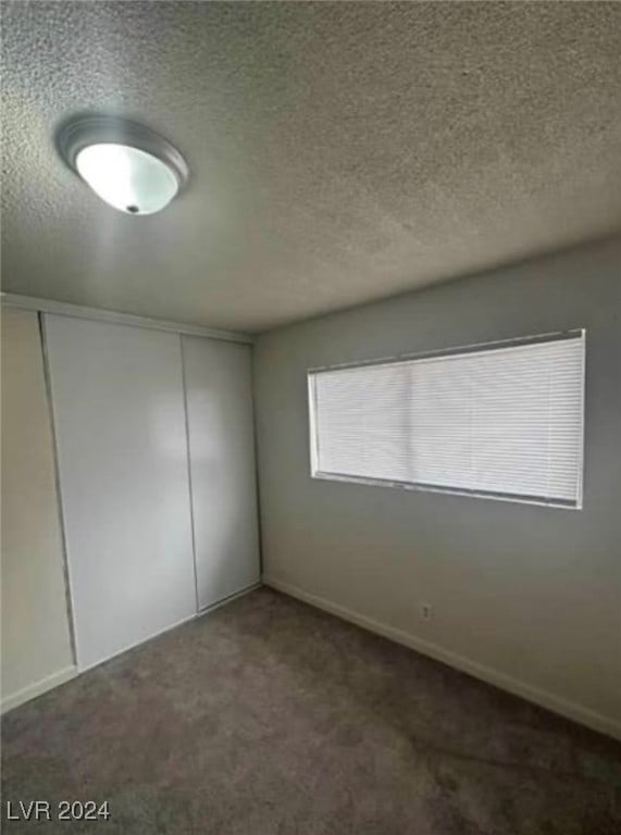 unfurnished bedroom with a textured ceiling, carpet, and a closet