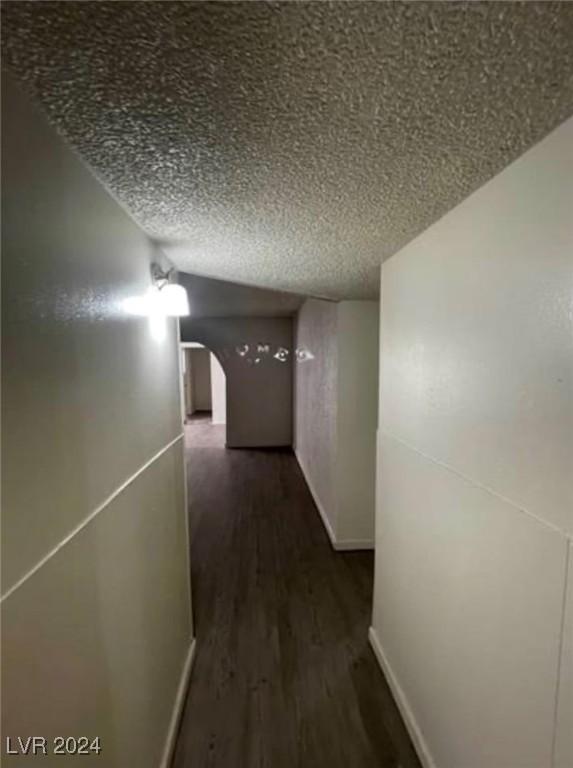 hallway with a textured ceiling and dark wood-type flooring