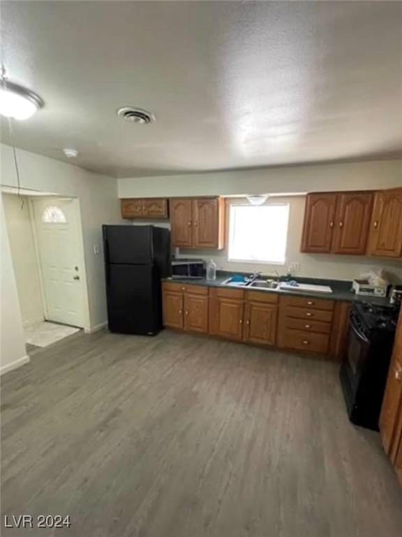 kitchen featuring sink, range, black fridge, and light hardwood / wood-style floors