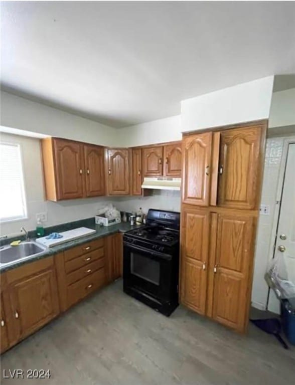 kitchen with black range with electric stovetop, sink, and light hardwood / wood-style flooring