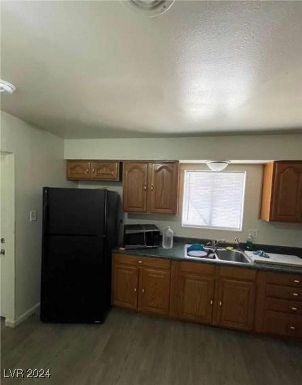 kitchen featuring sink, black refrigerator, and wood-type flooring