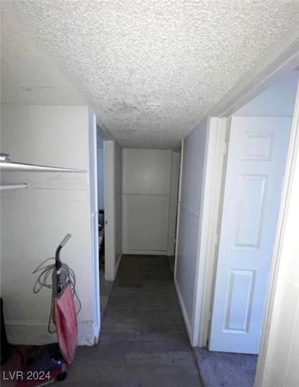 corridor with a textured ceiling and wood-type flooring