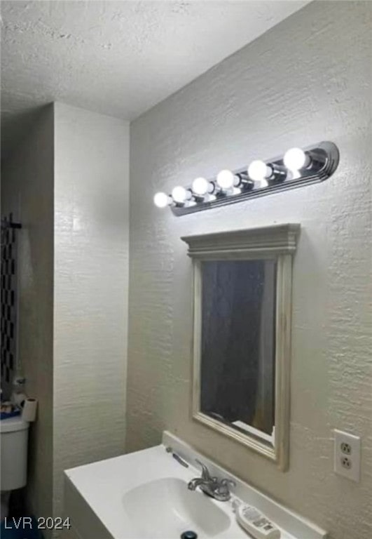 bathroom with sink, a textured ceiling, and toilet