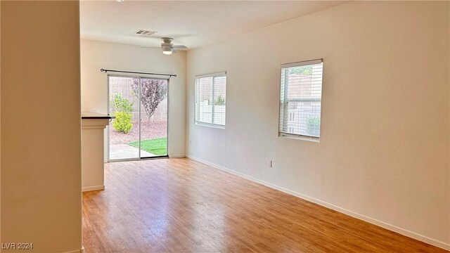 empty room featuring light wood finished floors, baseboards, visible vents, and a wealth of natural light