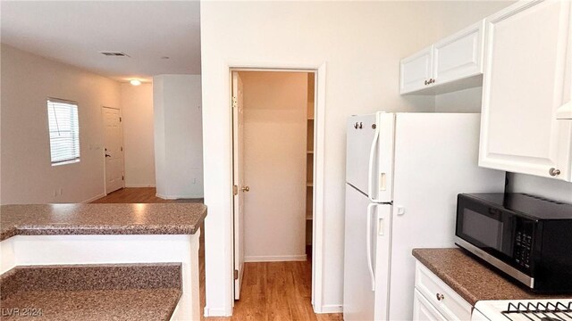 kitchen featuring visible vents, white cabinets, black microwave, and light wood finished floors