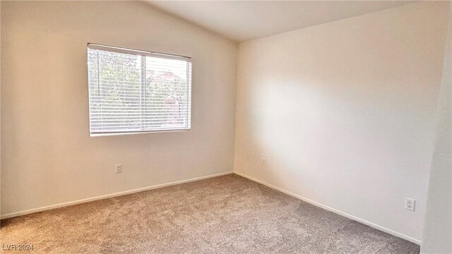 spare room with baseboards, carpet floors, and vaulted ceiling