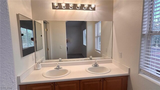 bathroom featuring double vanity, a textured wall, and a sink