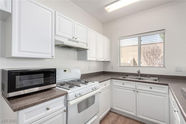 9333 Leaping Deer Pl Unit 102, Las Vegas, NV 89178 - kitchen featuring under cabinet range hood, white range with gas stovetop, a sink, stainless steel microwave, and white cabinets