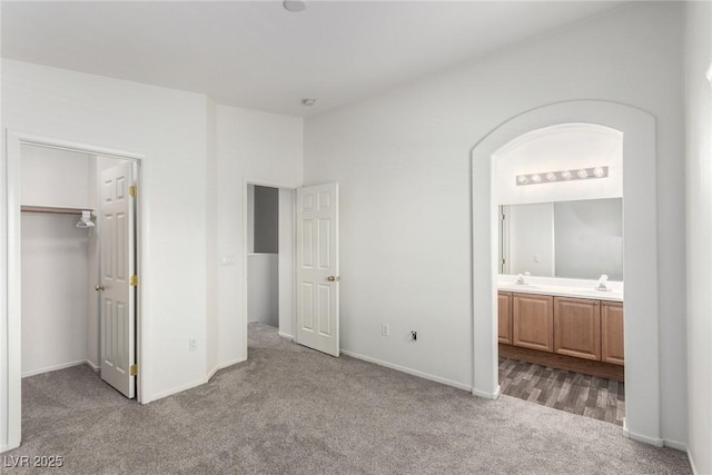 9333 Leaping Deer Pl Unit 102, Las Vegas, NV 89178 - unfurnished bedroom featuring carpet floors, a walk in closet, baseboards, ensuite bathroom, and a sink