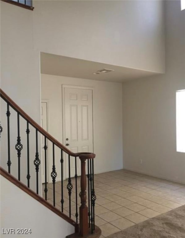 stairs with a towering ceiling and light tile patterned floors