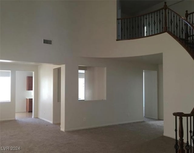 carpeted spare room featuring a high ceiling