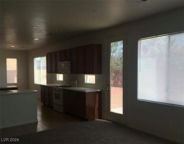 kitchen featuring dark brown cabinets, light tile patterned flooring, and white electric stove