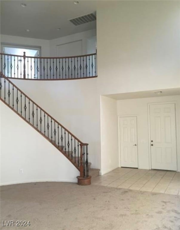 stairway with a towering ceiling and carpet floors