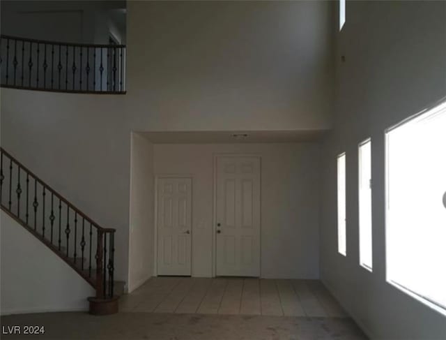 foyer featuring a towering ceiling, tile patterned floors, and plenty of natural light