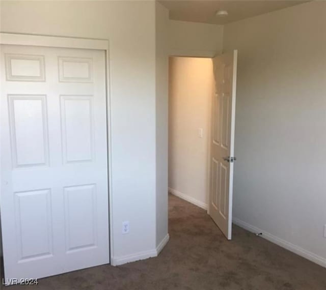 unfurnished bedroom featuring dark colored carpet and a closet