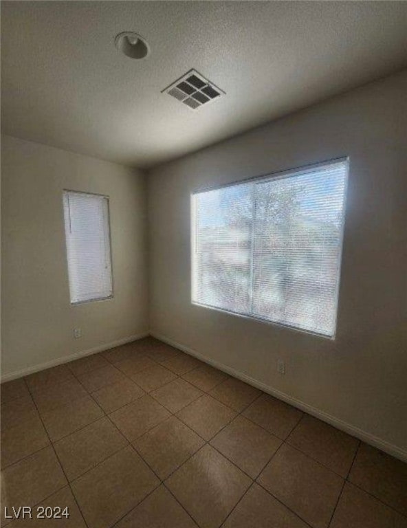 tiled spare room with a textured ceiling