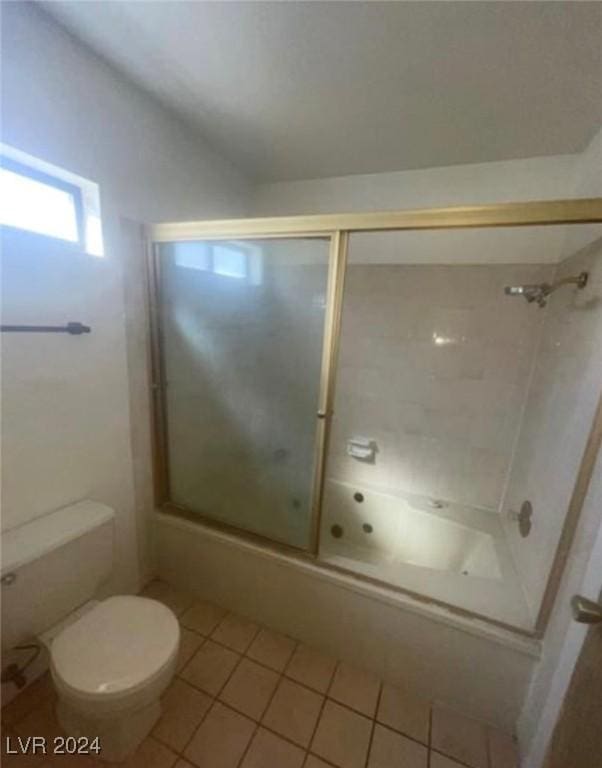 bathroom with toilet, tile patterned floors, and bath / shower combo with glass door