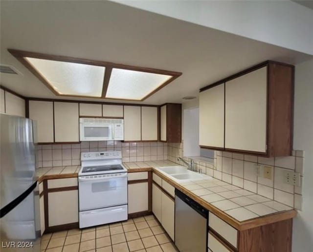 kitchen featuring sink, appliances with stainless steel finishes, tasteful backsplash, tile counters, and light tile patterned flooring