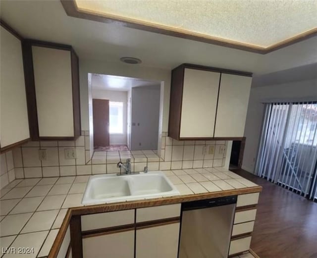 kitchen with sink, tasteful backsplash, stainless steel dishwasher, tile countertops, and white cabinets