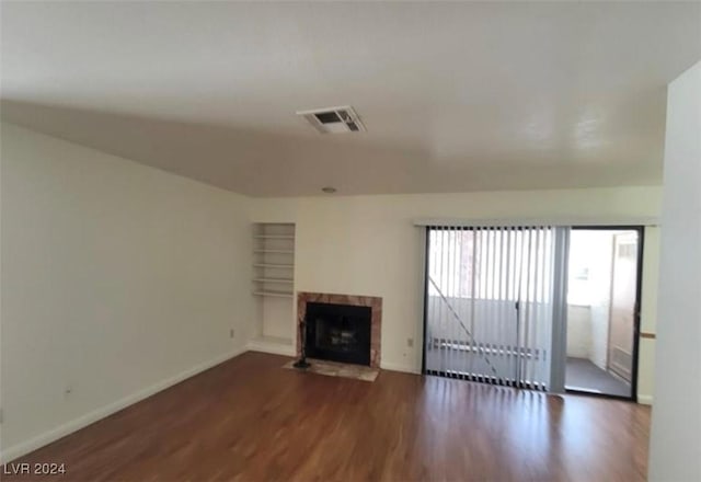 unfurnished living room with dark hardwood / wood-style flooring and a tiled fireplace