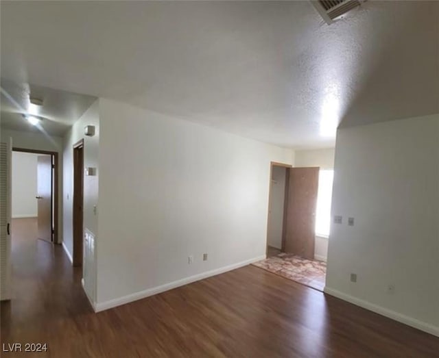 spare room with a textured ceiling and dark wood-type flooring