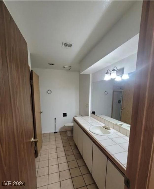 bathroom with tile patterned flooring, toilet, a shower, and vanity