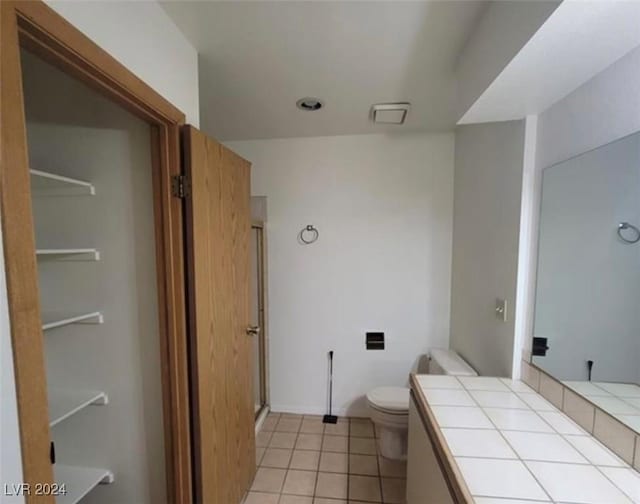 bathroom featuring tile patterned floors, toilet, an enclosed shower, and vanity