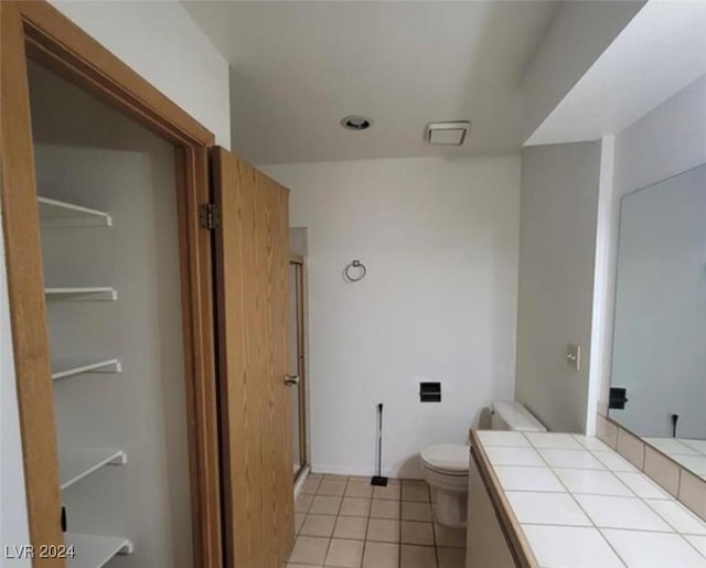 bathroom with tile patterned floors, vanity, toilet, and a shower with door