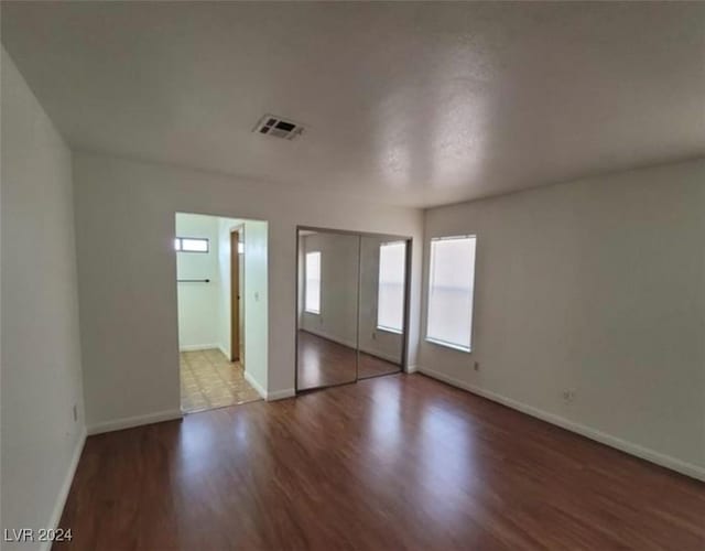 unfurnished bedroom with connected bathroom and hardwood / wood-style flooring