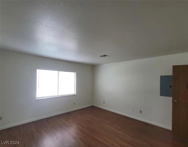 spare room with electric panel and dark hardwood / wood-style floors