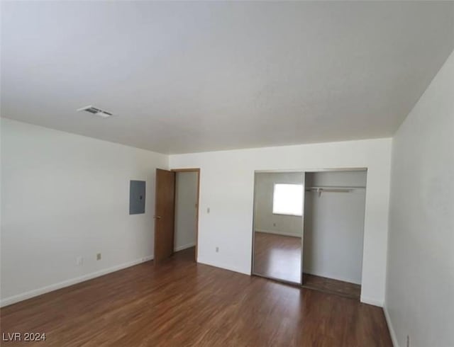 unfurnished bedroom featuring a closet, electric panel, and dark hardwood / wood-style floors