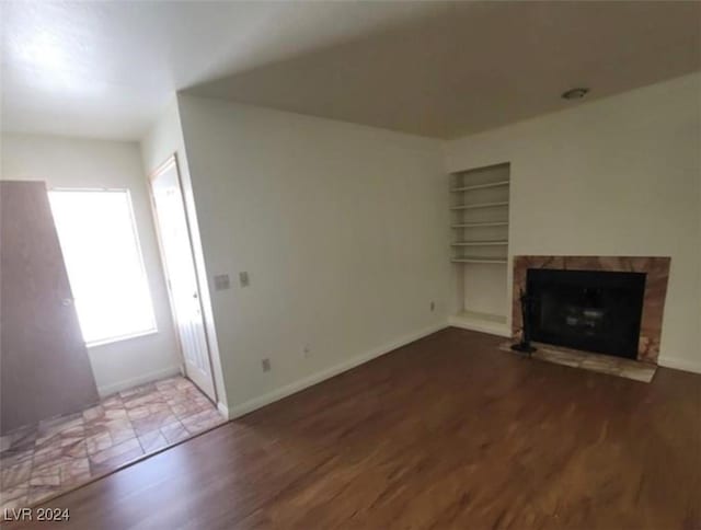 unfurnished living room featuring built in features and wood-type flooring