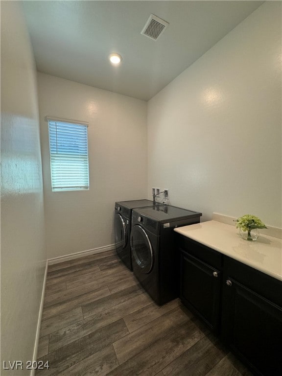 laundry room featuring dark hardwood / wood-style floors, cabinets, and washing machine and dryer