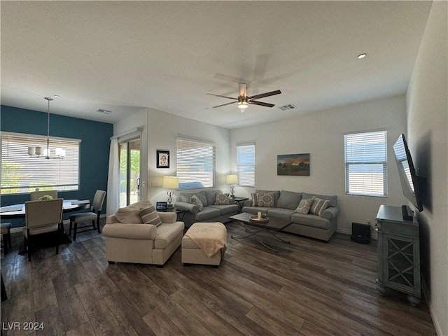 living area featuring baseboards, visible vents, dark wood-style flooring, and ceiling fan with notable chandelier