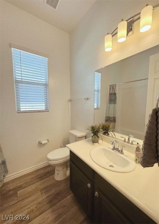 bathroom featuring toilet, wood finished floors, visible vents, vanity, and baseboards