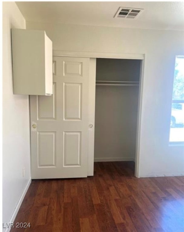 unfurnished bedroom with dark hardwood / wood-style flooring and a closet