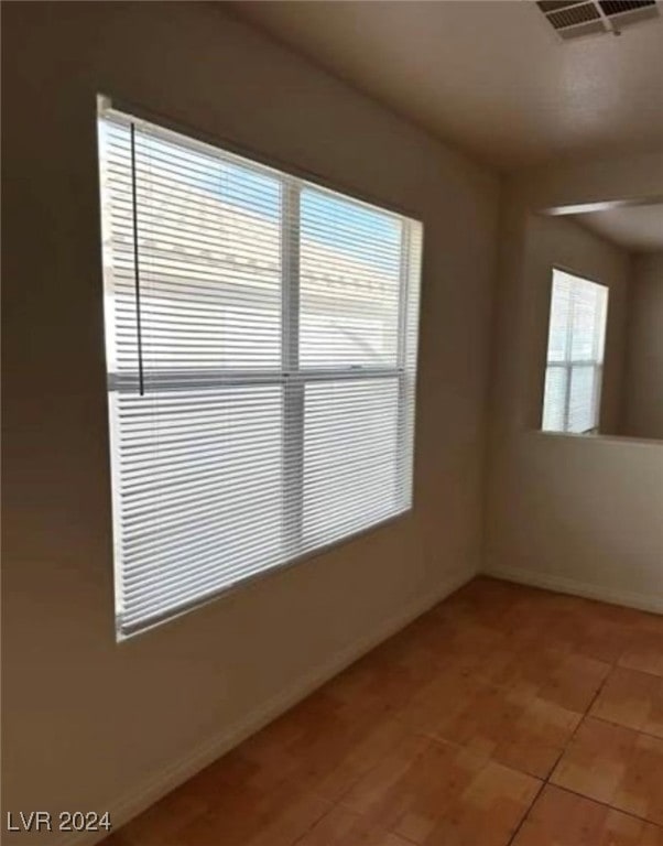 tiled spare room featuring a healthy amount of sunlight