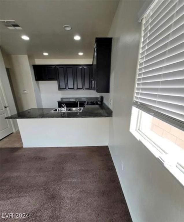 kitchen with kitchen peninsula, sink, and dark colored carpet