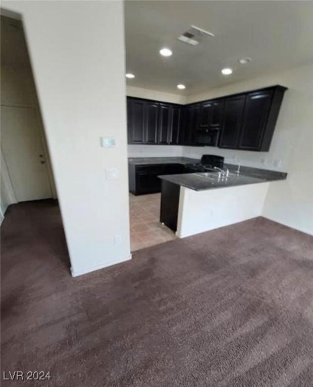 kitchen featuring sink, light colored carpet, and kitchen peninsula