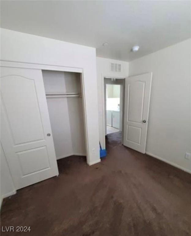 unfurnished bedroom featuring dark carpet and a closet