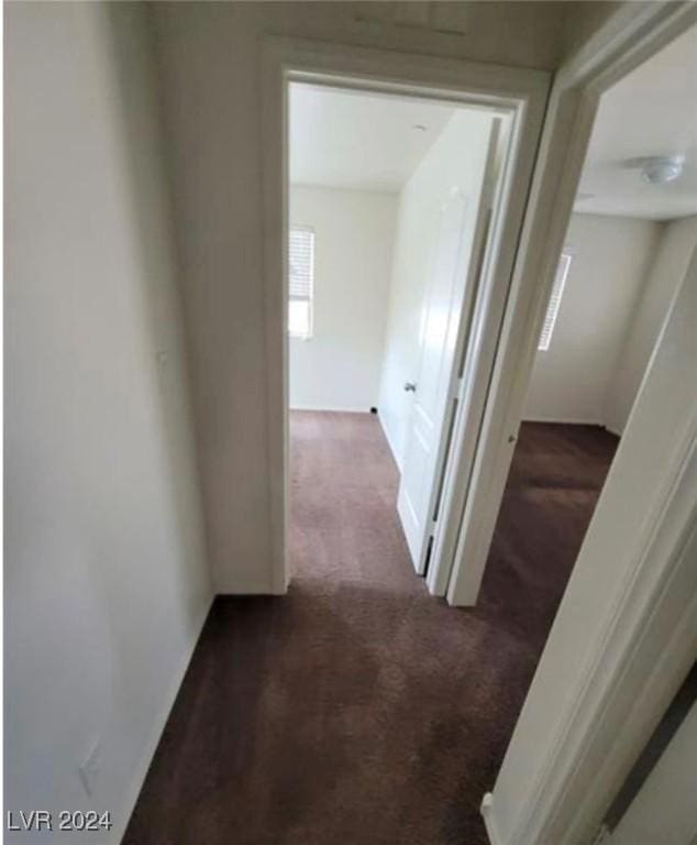 hallway featuring dark colored carpet