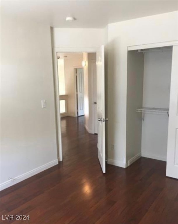 unfurnished bedroom with dark wood-type flooring and a closet