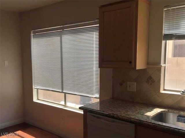 kitchen with decorative backsplash, dark stone counters, hardwood / wood-style flooring, dishwasher, and sink