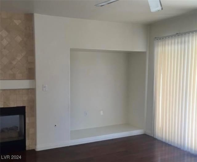 unfurnished living room featuring dark wood-type flooring, ceiling fan, and a wealth of natural light