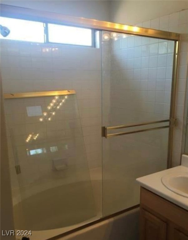 bathroom with enclosed tub / shower combo, vanity, and a healthy amount of sunlight