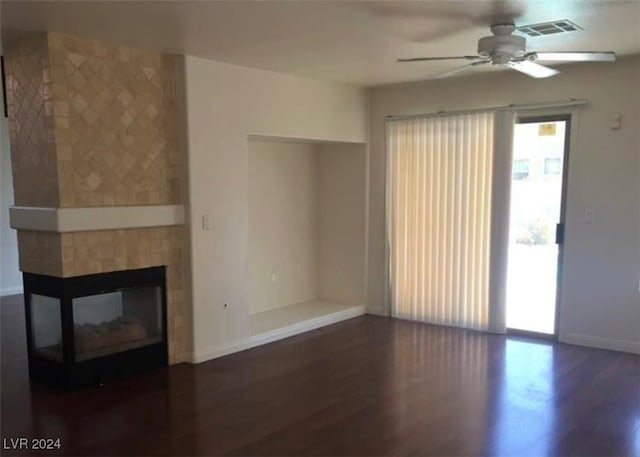 unfurnished living room with ceiling fan, a tiled fireplace, and hardwood / wood-style flooring